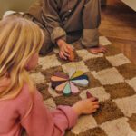 Ferm Living bloembladjes speelblokkFerm Living petal speelblokken Montessori van gekleurd hout waarmee een jongen en een meisje spelen